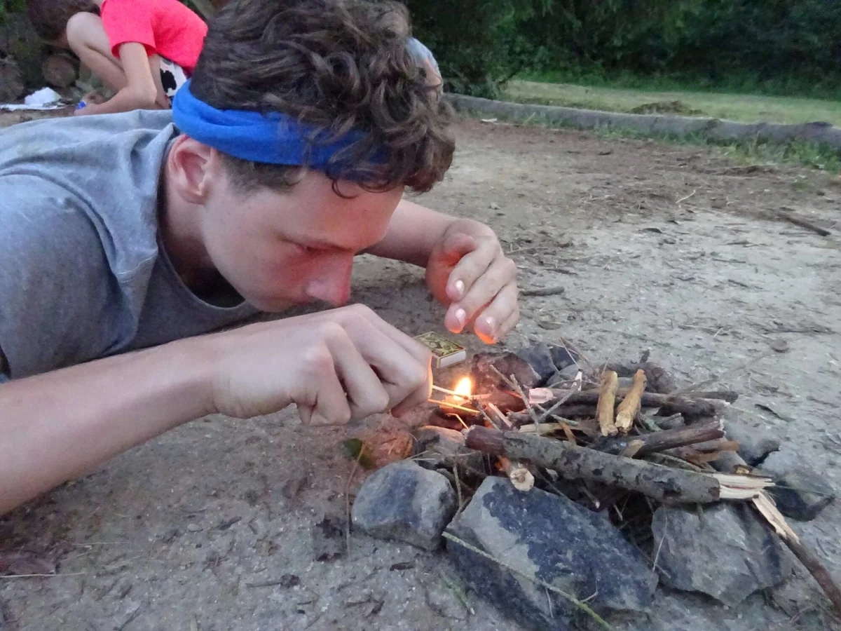 Dítě rozdělává oheň při táborové výzvě